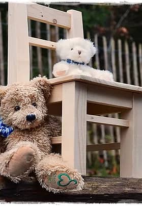 Ein Sessel aus Holz mit zwei Plüschteddys